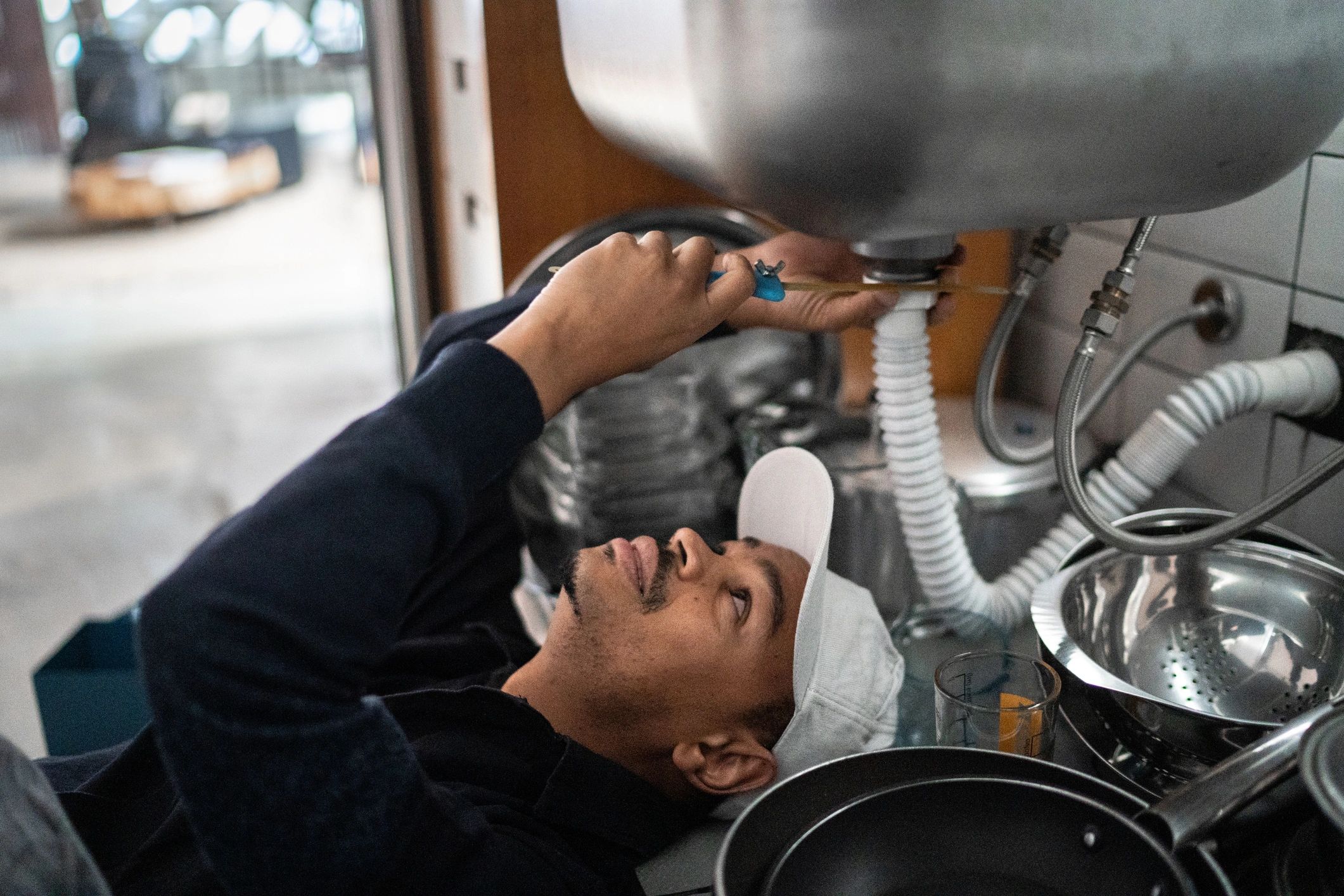Plumber repairing a water pipe beneath a kitchen sink